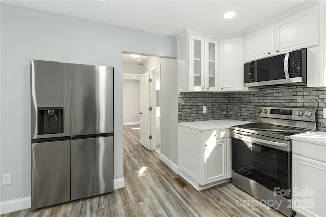 kitchen featuring white cabinetry, decorative backsplash, stainless steel appliances, and light countertops