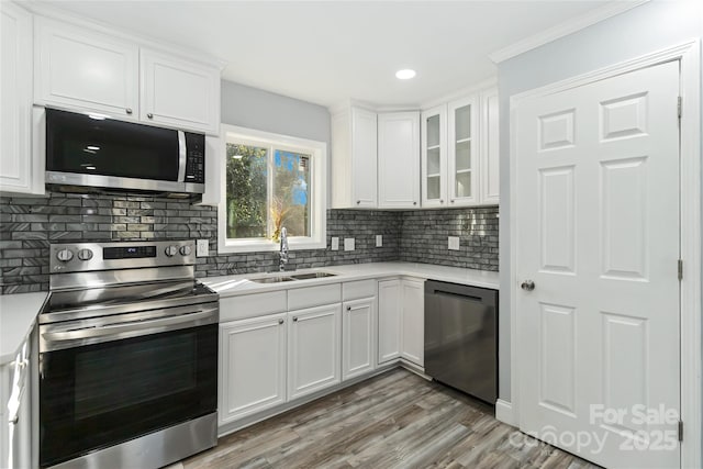 kitchen with a sink, white cabinets, light countertops, appliances with stainless steel finishes, and tasteful backsplash