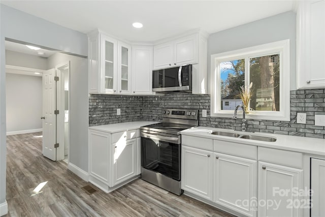 kitchen with stainless steel appliances, light countertops, a sink, and white cabinetry