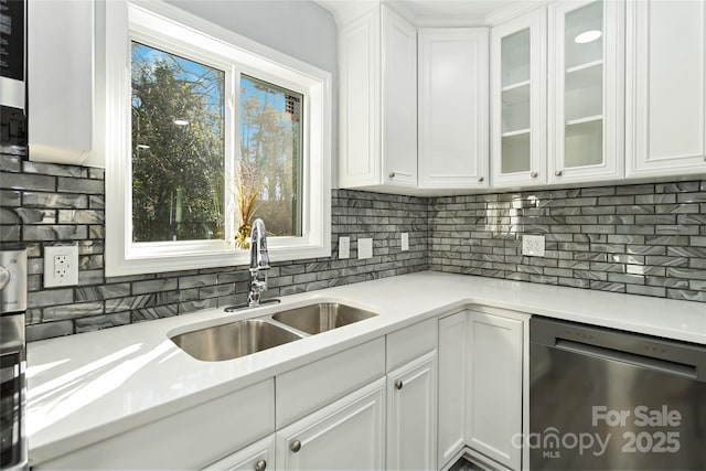 kitchen with light countertops, white cabinetry, a sink, and stainless steel dishwasher