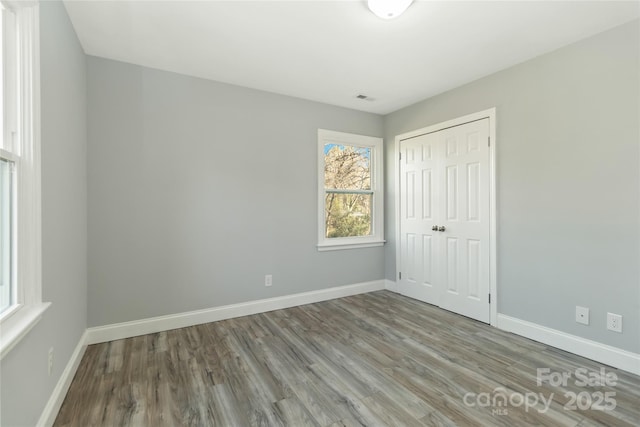 unfurnished bedroom with a closet, baseboards, and wood finished floors