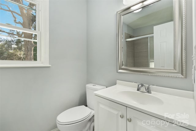 full bathroom with a shower with shower door, vanity, and toilet