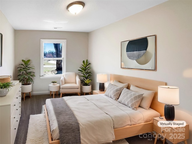 bedroom featuring baseboards, visible vents, and wood finished floors