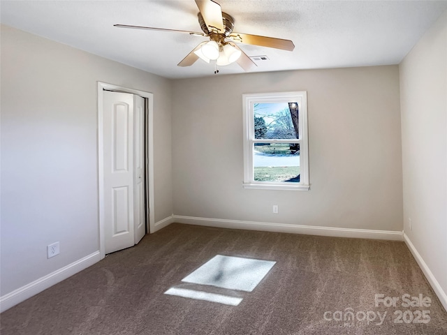 unfurnished room with carpet floors, visible vents, ceiling fan, and baseboards