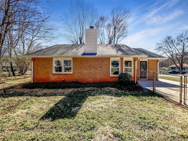 exterior space with a front yard, brick siding, fence, and a chimney