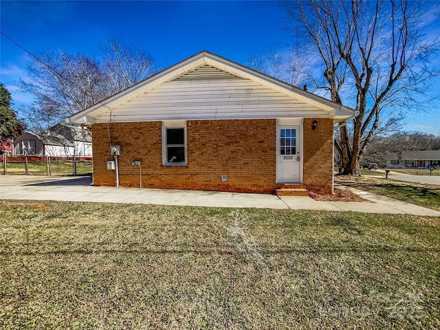 back of property featuring entry steps, a yard, and brick siding