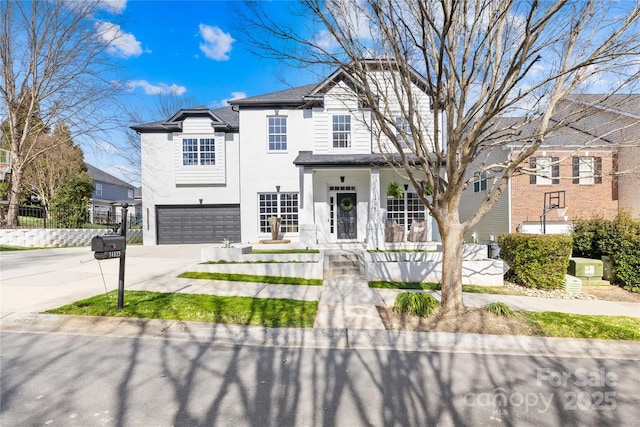 view of front of home with an attached garage, fence, covered porch, and driveway