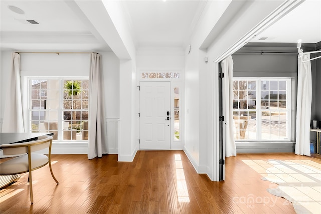 foyer featuring plenty of natural light, wood finished floors, and ornamental molding