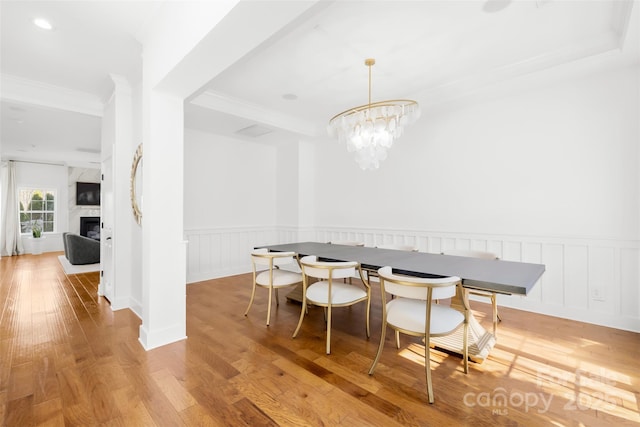 dining space featuring wainscoting, hardwood / wood-style floors, and crown molding