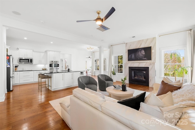 living room with visible vents, a premium fireplace, recessed lighting, light wood-style flooring, and a ceiling fan