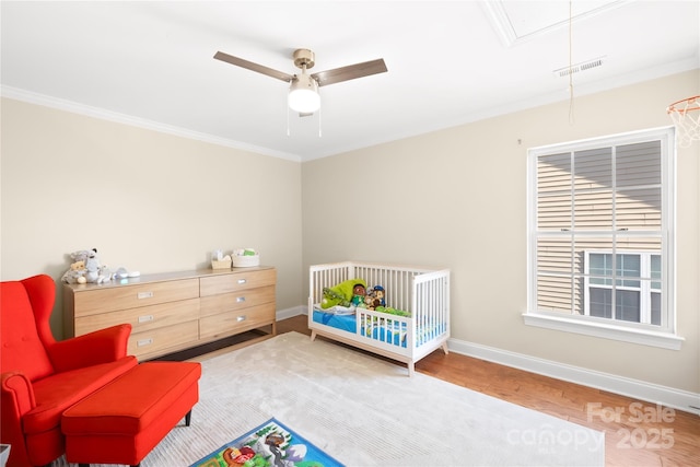 bedroom with visible vents, baseboards, attic access, and a crib