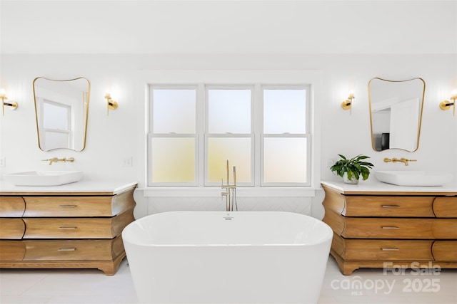 bathroom with a sink, a freestanding tub, and two vanities