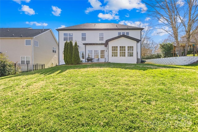 back of property featuring a lawn and fence