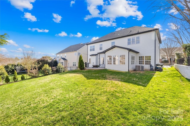 rear view of property featuring a patio area, a lawn, central AC, and a fenced backyard