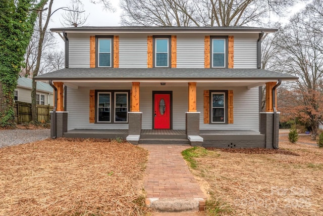 view of front of property featuring covered porch, a shingled roof, and fence