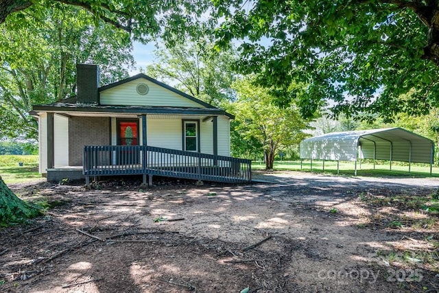 view of front of home with a detached carport, brick siding, covered porch, and a chimney