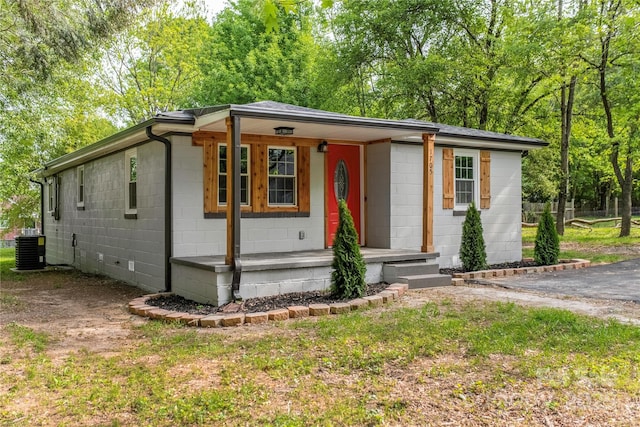 view of front of property with a porch, central AC, and concrete block siding