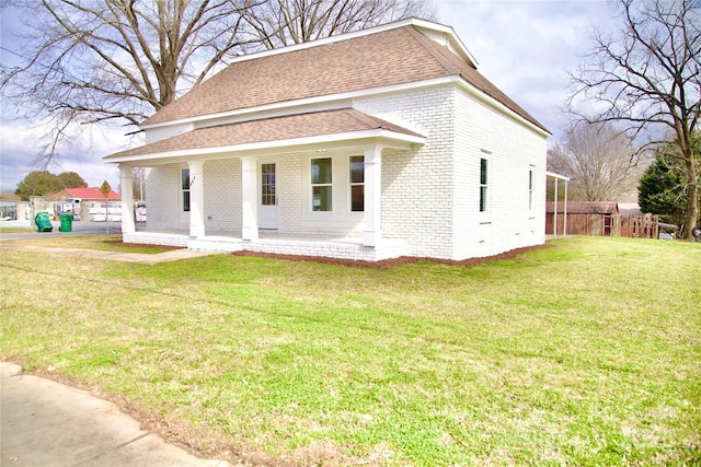 exterior space featuring a yard, brick siding, a shingled roof, and fence