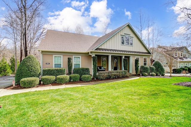 view of front facade featuring a shingled roof, metal roof, covered porch, a standing seam roof, and a front lawn