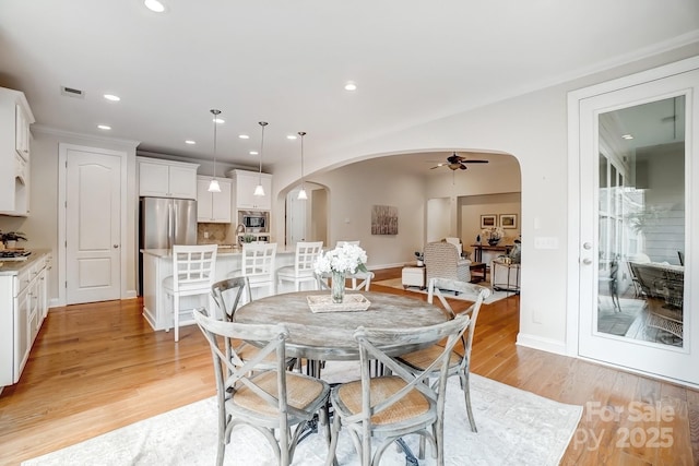 dining room with a ceiling fan, arched walkways, light wood finished floors, and recessed lighting