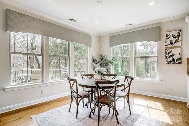 dining area with light wood-style flooring, visible vents, baseboards, and ornamental molding