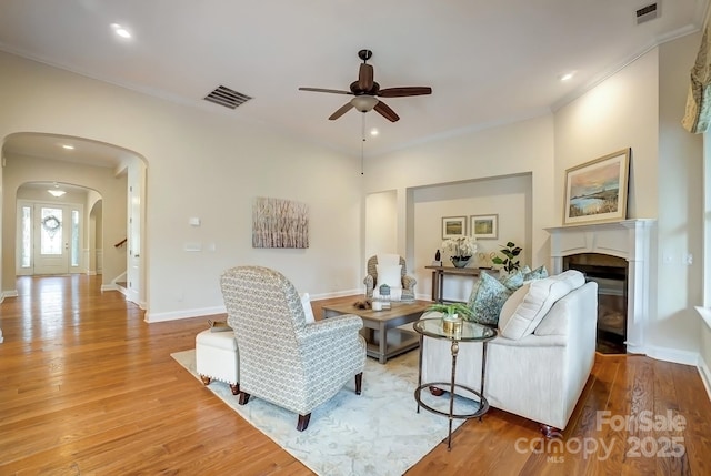 living area featuring arched walkways, visible vents, and wood finished floors