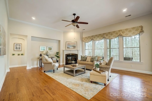 living room with a glass covered fireplace, crown molding, baseboards, and hardwood / wood-style flooring