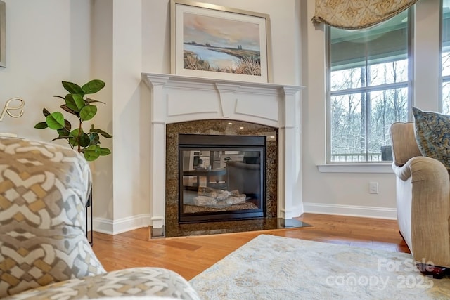 sitting room featuring wood finished floors, a high end fireplace, and baseboards