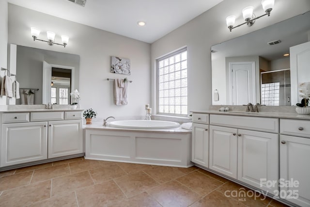 bathroom featuring a bath, a shower stall, visible vents, and a sink