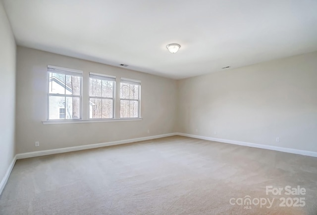 carpeted spare room with visible vents and baseboards