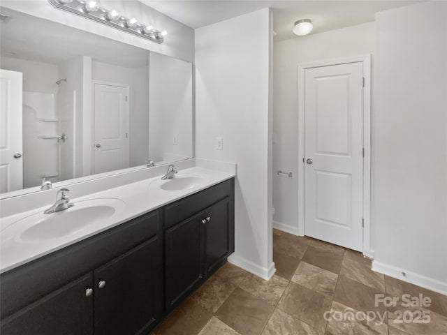 bathroom featuring double vanity, a sink, toilet, and baseboards