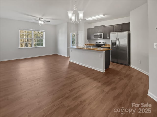 kitchen with baseboards, open floor plan, appliances with stainless steel finishes, dark wood finished floors, and pendant lighting