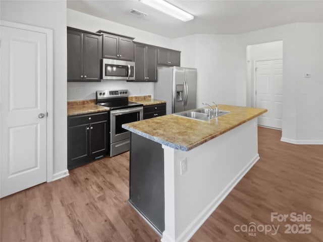 kitchen with visible vents, light wood-style flooring, appliances with stainless steel finishes, a kitchen island with sink, and a sink