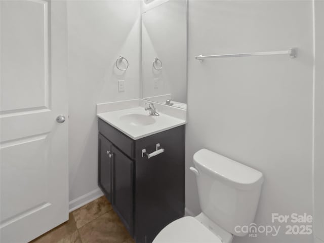 half bath with toilet, vanity, and tile patterned floors