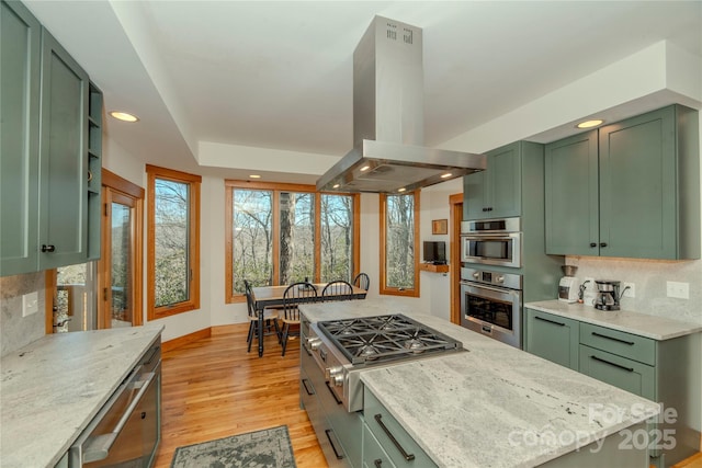 kitchen featuring island range hood, light wood-style floors, stainless steel appliances, and green cabinetry