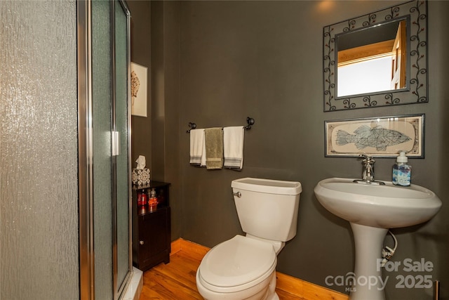 full bathroom featuring a shower stall, toilet, wood finished floors, and baseboards