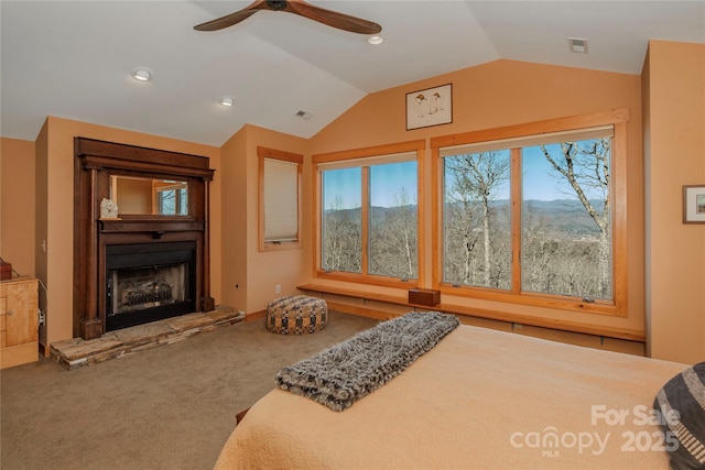 bedroom featuring carpet flooring, visible vents, a fireplace with raised hearth, and lofted ceiling