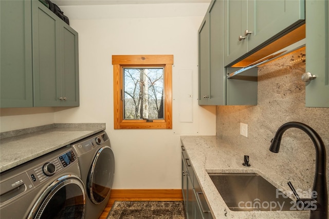 laundry area featuring washer and dryer, cabinet space, baseboards, and a sink