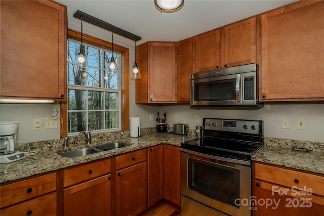 kitchen featuring a sink, light stone countertops, brown cabinets, and stainless steel appliances