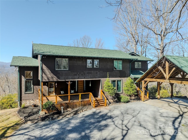 view of front facade with aphalt driveway, covered porch, and a shingled roof