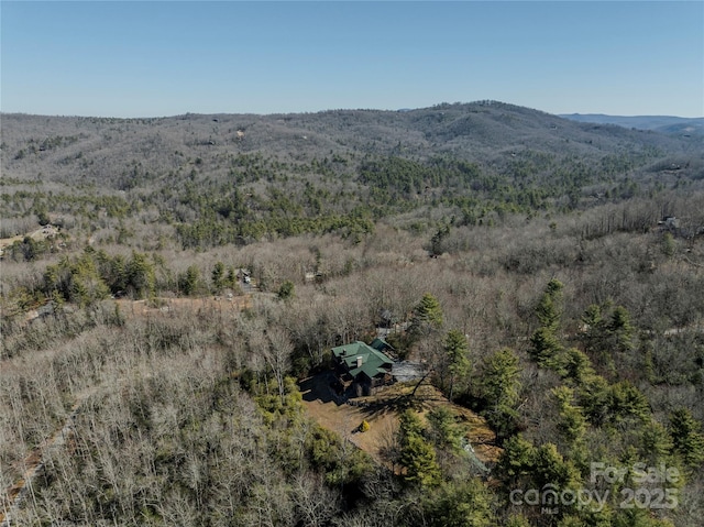 aerial view featuring a wooded view and a mountain view