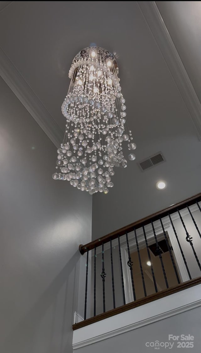 details featuring ornamental molding, visible vents, and a notable chandelier