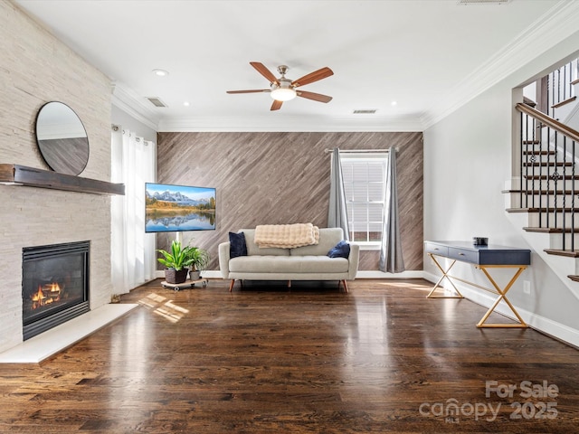 living room featuring a fireplace, baseboards, crown molding, and wood finished floors