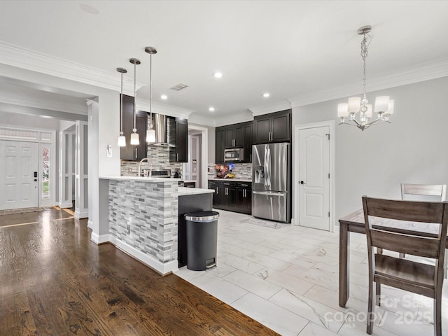 kitchen featuring tasteful backsplash, visible vents, wall chimney exhaust hood, appliances with stainless steel finishes, and light countertops