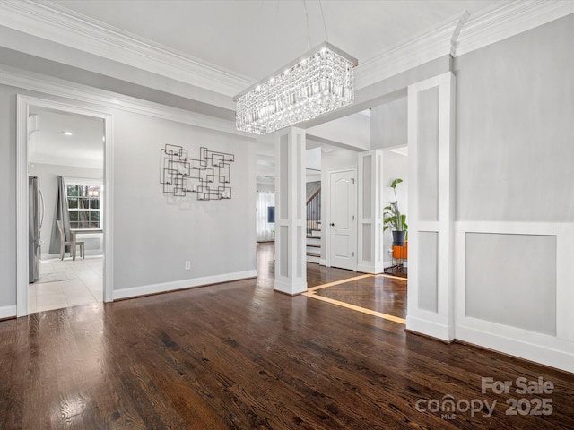 unfurnished dining area with stairs, a chandelier, wood finished floors, and crown molding