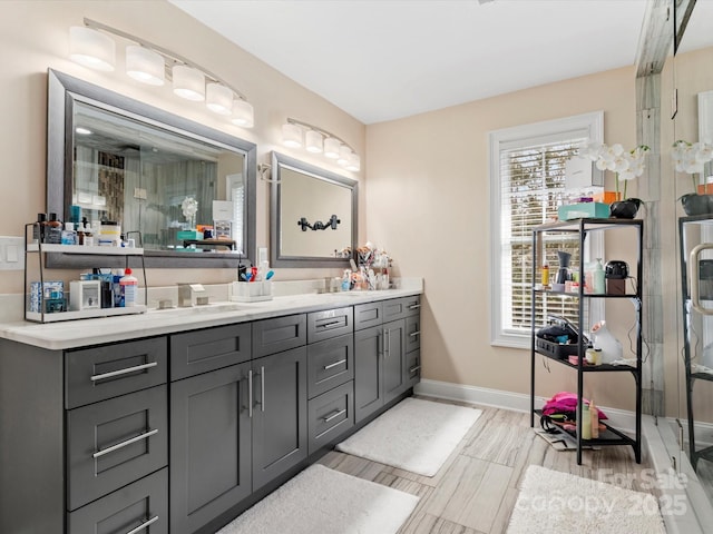 bathroom featuring a shower with door, vanity, and baseboards