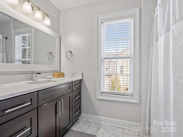 full bath featuring marble finish floor, vanity, a wealth of natural light, and baseboards