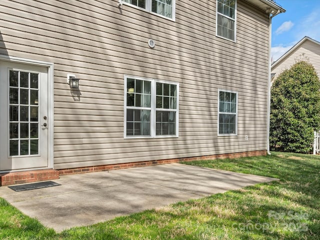 view of side of property with a patio area and a lawn