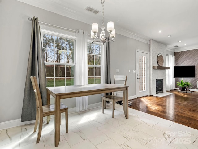 dining space featuring a large fireplace, crown molding, visible vents, and baseboards