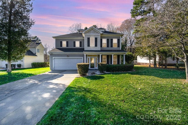 traditional-style house with a garage, concrete driveway, and a front lawn